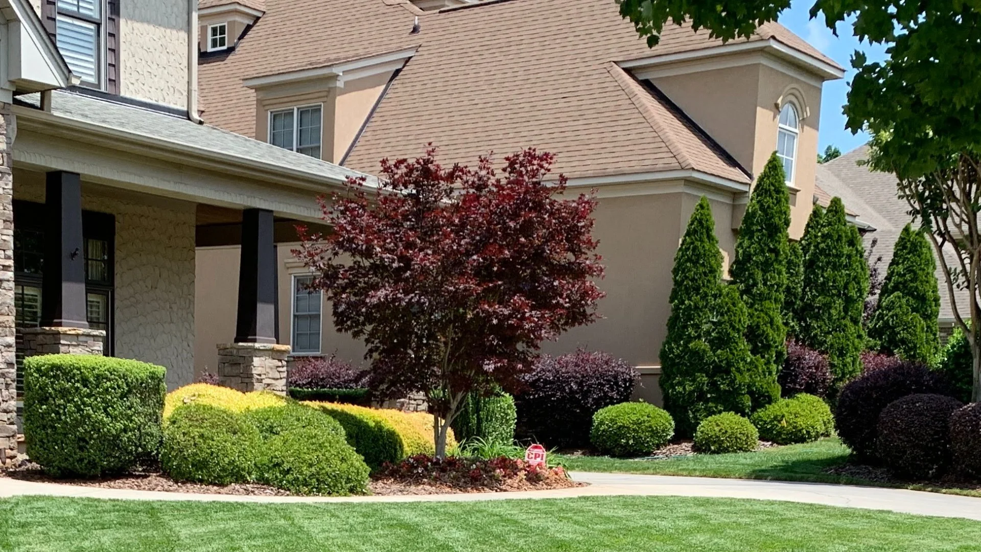 House in Charlotte, NC surrounded by trees, lawn, shrubs, and flowers.