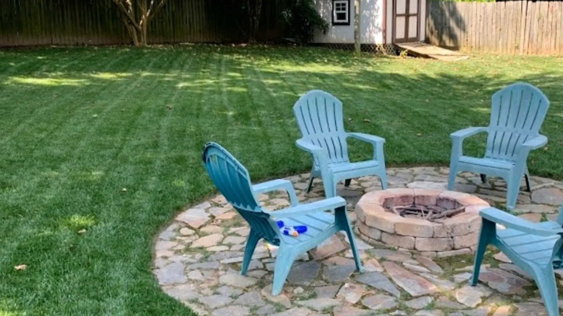 Large backyard in Charlotte, NC with patio, fire pit, and lush green lawn.