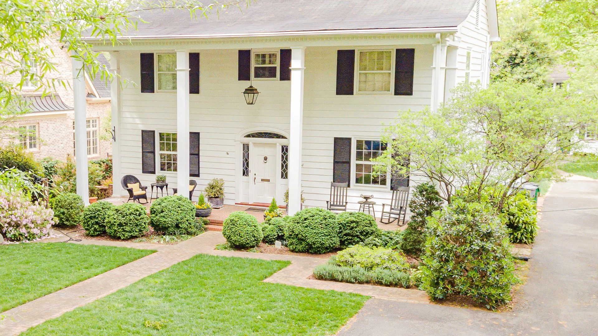 House in Charlotte, NC surrounded by trees, lawn, shrubs, and flowers.